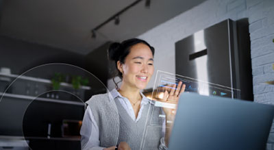 Smiling individual interacts with a holographic display projected from a laptop