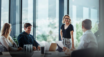 Five smiling individuals hold a meeting around a table in a modern office environment