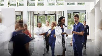 Medical professionals are in discussion and in motion within a well-lit hospital lobby