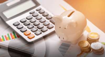 A desk with financial documents, a calculator and a white piggy bank