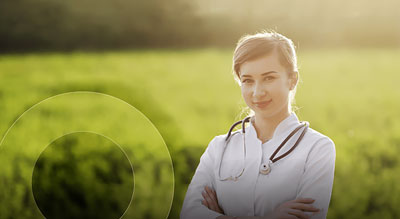 A confident medical professional stands outdoors in a bright and uplifting setting