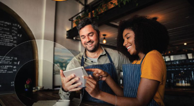 Two individuals in a café looking at a tablet with a document on the table