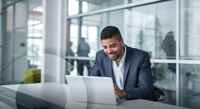 A person working on a laptop at an office desk.