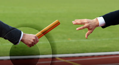 A person passes a golden baton to another person
