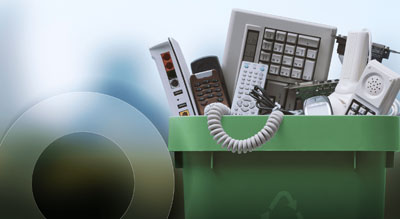 A green recycling bin filled with various old and outdated telephones, symbolizing electronic waste recycling