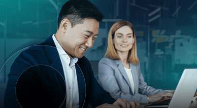 Two professionals working on laptops in a modern office setting