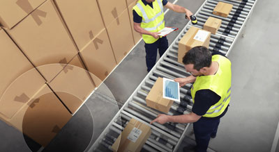 Efficient workers manage packages on a conveyor belt in a warehouse, showcasing an organized distribution system