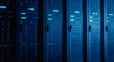 Rows of server racks in a data center, illuminated by blue light.