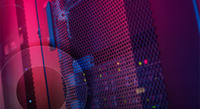 Close-up of a server rack with mesh panels and colorful indicator lights glowing in a dark, neon-lit data center environment