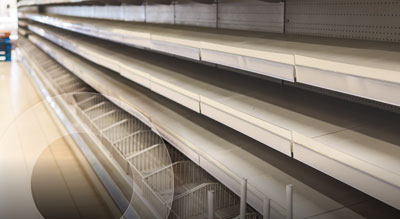 Empty store shelves stretching down an aisle, with no products stocked