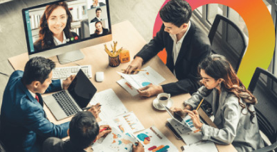 Group of individuals engaged in a discussion around a table cluttered with laptops, papers, and other office supplies