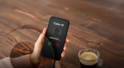 A hand holding a phone that displays a caller ID