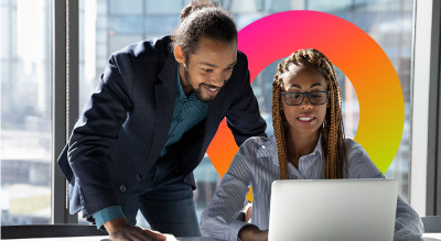 Two professionals in a well-lit office are engaged in a discussion while looking at a laptop