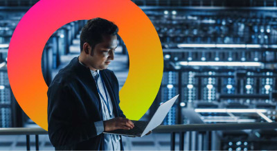 A person holding a laptop in a server room