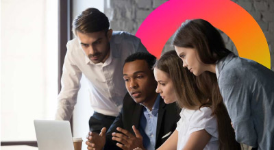 A group of professionals in business attire are engaged in a discussion around a laptop in a well-lit room