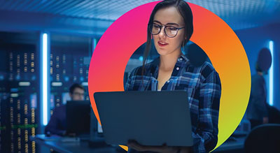 A person holding a laptop in a server room