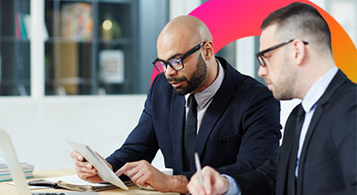 Two individuals in formal attire are engaged in a discussion or collaborative work.