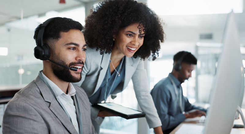 Three individuals are working in a modern office, with one person wearing a headset
