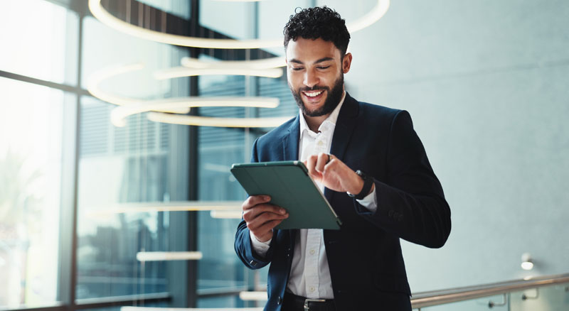 A smiling professional taps on the screen of a digital tablet
