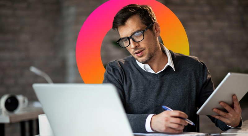 Man looking at laptop while working on tablet