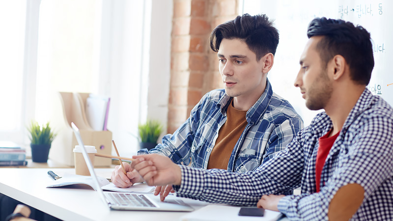 Two people review information together on a laptop