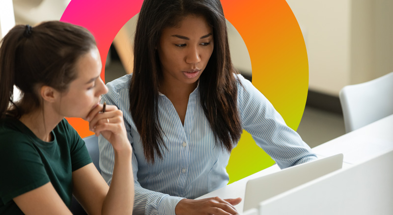 Two women look pensive as they review information on a laptop