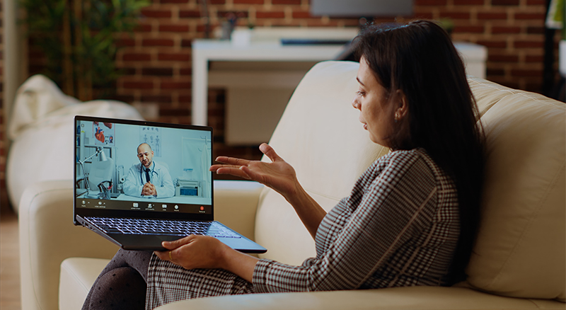 A person seated on a couch, focused on her laptop, creating a cozy and productive home environment