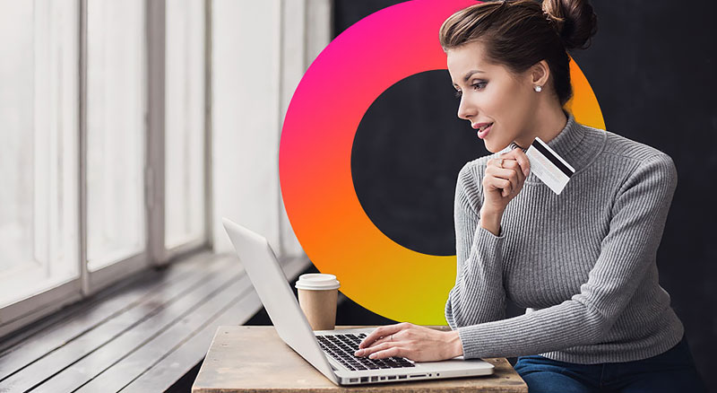 Woman holds credit card while using laptop