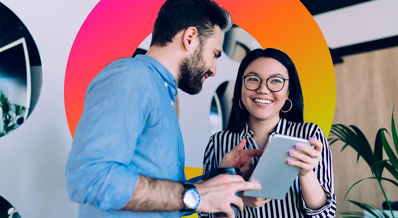 Smiling man and woman look at a digital tablet