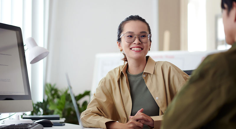 Woman smiling infront of desktop monitor