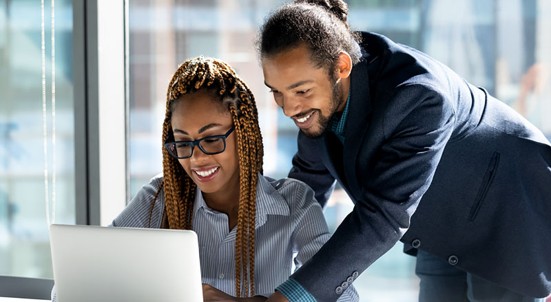 A man assists his coworker using a laptop