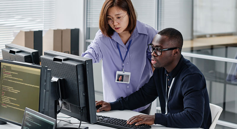 A manager points at her employee's computer monitor