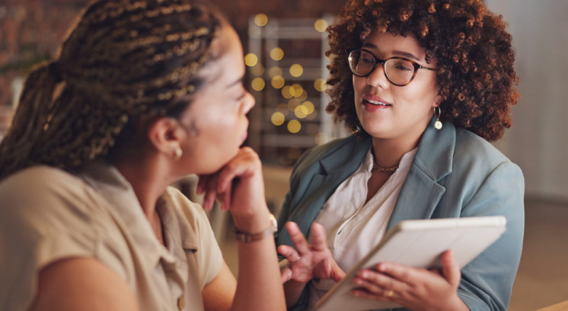 Two people discuss information on a digital tablet