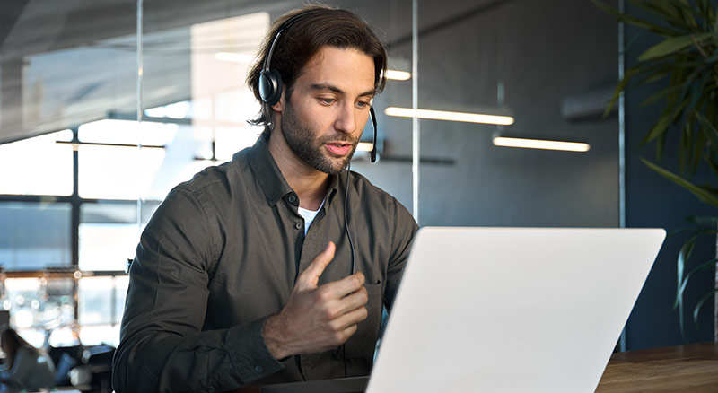 A representative talks through their headset while operating a laptop